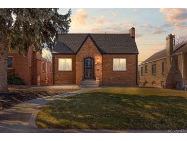 Charming brick home with an ornate front door, well-manicured lawn, and a walkway leading to the entrance at 1467 Clermont St, Denver, CO 80220