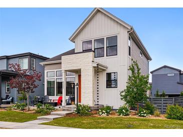 Attractive home with a covered porch, orange front door, and manicured lawn with flower beds at 6237 Stable View St, Castle Pines, CO 80108
