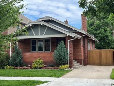 Charming brick home with landscaped front yard, featuring a mix of trees and shrubbery at 660 S Clarkson St, Denver, CO 80209