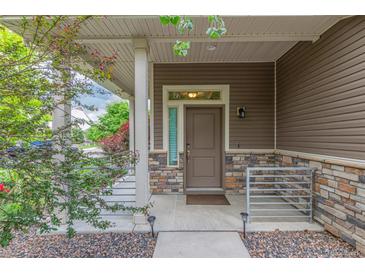 Inviting covered porch with stone accents, a charming entry door, and manicured landscaping offers great curb appeal at 18112 E 104Th Way, Commerce City, CO 80022