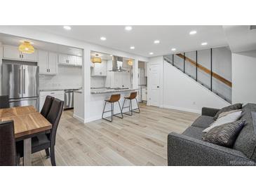 Open-concept living room features modern decor, breakfast bar, and staircase at 7995 E Mississippi Ave # A4, Denver, CO 80247