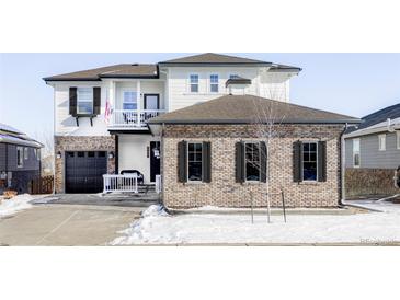 Two-story home with brick and siding, gray garage door, and balcony at 6918 S Riverwood Way, Aurora, CO 80016