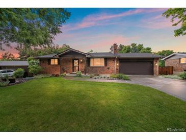 Charming brick home with a well-manicured lawn and a two-car garage offers great curb appeal at 7077 Dudley Dr, Arvada, CO 80004