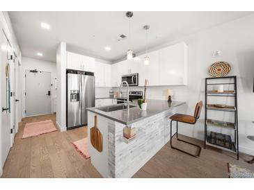 Modern kitchen featuring stainless steel appliances, gray countertops and an island with breakfast bar at 1898 S Bannock St # 202, Denver, CO 80223