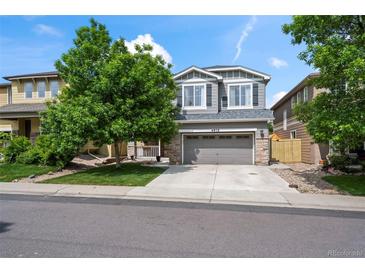Charming two-story home with gray siding, a well-manicured lawn, and a two car garage at 4975 S Zephyr St, Littleton, CO 80123