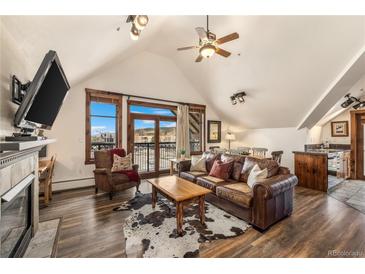 Open living room with vaulted ceiling, balcony, fireplace, and leather sofa at 505 S Main St # 2207, Breckenridge, CO 80424