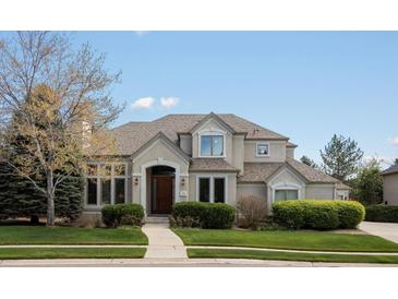 Charming two-story home with a beautiful lawn, shrubs, and a well-lit entryway at 5700 S Benton Cir, Littleton, CO 80123