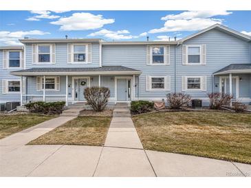 Charming townhome with light blue siding, white trim, a well-kept lawn, and a cozy front porch at 6240 Everett Ct # F, Arvada, CO 80004