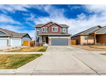 Two-story home featuring a gray exterior, red accents, and a spacious driveway leading to a two-car garage at 6707 6Th St, Frederick, CO 80530