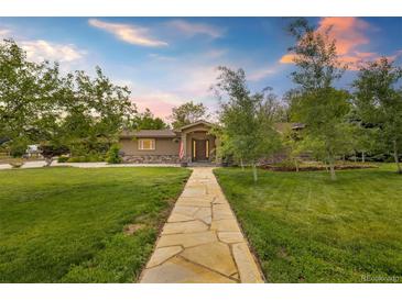Charming ranch-style home with stone walkway and mature trees, offering a warm and inviting curb appeal at 10380 W Warren Ave, Lakewood, CO 80227