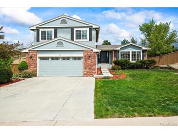 Charming two-story home featuring blue siding, a brick facade, and a well-manicured lawn at 705 Prairie Ridge Rd, Highlands Ranch, CO 80126