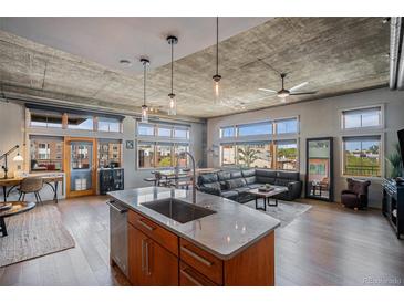Spacious living room featuring an island kitchen, hardwood floors, exposed concrete ceilings and plenty of natural light at 1925 W 32Nd Ave # 404, Denver, CO 80211