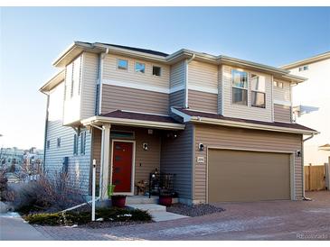 Two-story home featuring a tan-colored exterior, an attached garage, and a brick-paved driveway at 2848 Merry Rest Way, Castle Rock, CO 80109