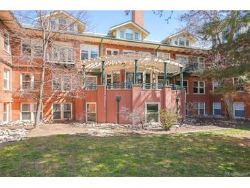 Charming red brick building featuring a unique covered patio and a well-manicured green lawn area at 3249 W Fairview Pl # 106, Denver, CO 80211