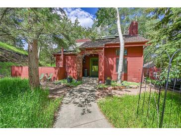 Charming red home with a landscaped front yard and a stone pathway leading to the inviting front door at 23626 Genesee Village Rd, Golden, CO 80401
