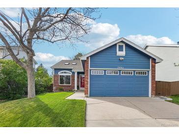 Charming blue home featuring a well-manicured lawn, brick accents, and a two-car garage at 7061 Palisade Dr, Highlands Ranch, CO 80130