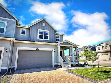 Charming two-story home featuring a gray exterior, brick driveway, and attached garage at 700 Lillibrook Pl, Erie, CO 80026