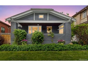 Charming home featuring a brick facade, covered front porch, and meticulously maintained landscaping at 3341 Newton St, Denver, CO 80211