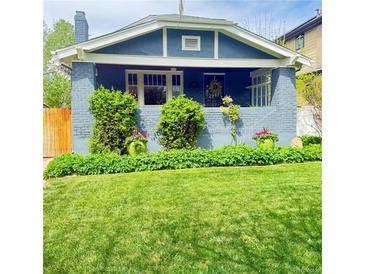 Charming blue home featuring a well-manicured lawn and lush landscaping in the front yard at 3341 Newton St, Denver, CO 80211