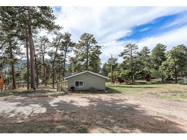 Charming exterior view with a well-maintained lawn, siding, a sun room, and mature trees in a serene setting at 4295 Picutis Rd, Indian Hills, CO 80454