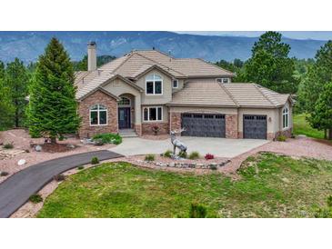 Charming home featuring a stone facade, three-car garage, and beautiful landscaping at 1127 Buttermilk Rd, Larkspur, CO 80118