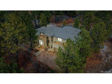 Beautiful home featuring a tile roof, large windows, and a private driveway surrounded by mature trees at 209 Saratoga Mine Dr, Castle Rock, CO 80108