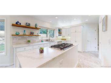 Bright kitchen with white cabinets, stainless steel appliances, and a center island with cooktop at 10886 Pheasant Run, Littleton, CO 80125