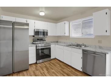 Well-lit kitchen with stainless steel appliances, white cabinetry, and marble-pattern countertops at 16651 E Arizona Pl, Aurora, CO 80017
