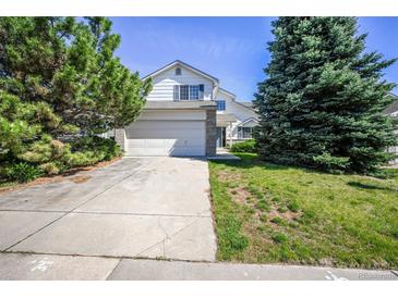 Charming two-story home featuring a two-car garage, well-maintained lawn, and mature trees on a sunny day at 11305 W Crestline Dr, Littleton, CO 80127