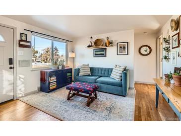 Bright living room with teal couch, wood floors, and entryway view at 4330 Bruce Randolph Ave, Denver, CO 80207