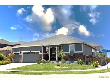 Charming single-story home featuring a well-manicured lawn, stone accents, and an attached two-car garage at 599 Fall River Ct, Brighton, CO 80601