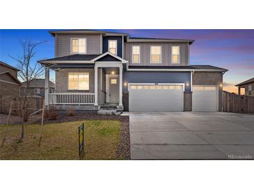 Two-story home featuring a two-car garage, covered front porch, and manicured lawn at 8374 E 132Nd Pl, Thornton, CO 80602