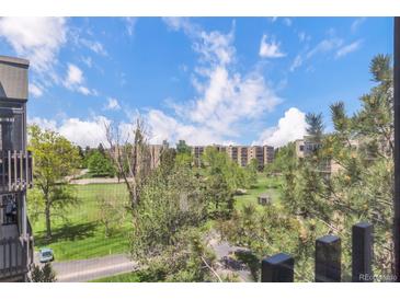 Scenic view of the golf course from a balcony shows lush green grass, tall trees, and blue skies with white clouds at 14001 E Marina Dr # 606, Aurora, CO 80014