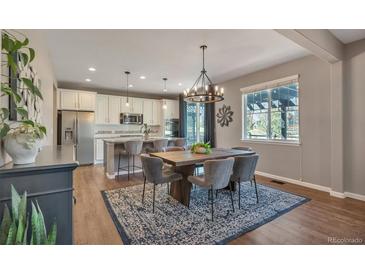 Open concept kitchen with stainless steel appliances, island seating, and connected dining area with stylish chandelier at 7665 Grady Cir, Castle Rock, CO 80108