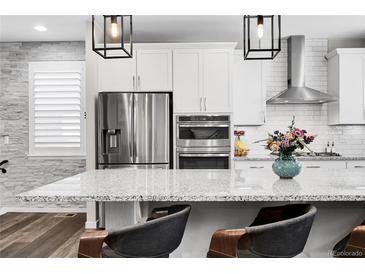 Bright kitchen features stainless steel appliances, white cabinetry, granite counters and a kitchen island with bar stool seating at 3560 Corsica Way, Castle Rock, CO 80109