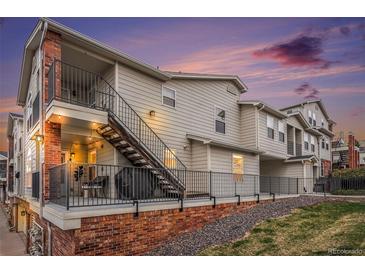 Exterior view of a modern townhouse featuring a private patio, stairs, and brick foundation at sunset at 1646 S Deframe St # B8, Lakewood, CO 80228