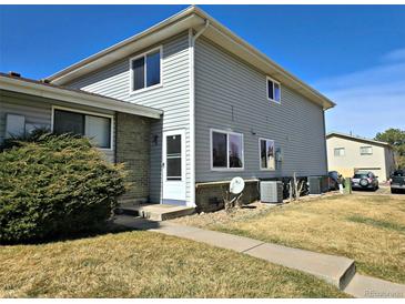 Two-story home with gray siding, brick accents, a well-manicured lawn, and a walkway leading to the front door at 3225 S Garrison St # 19, Lakewood, CO 80227