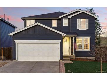Charming two-story home with a white garage door and a beautifully maintained front yard at 317 Bonanza Dr, Erie, CO 80516