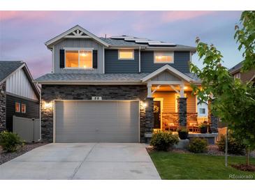 Charming two-story home featuring a stone facade, covered porch, and solar panels, perfect for modern living at 56 Magnolia Ct, Erie, CO 80516