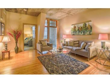 Bright living room with hardwood floors, modern furniture, and an open balcony with views at 275 S Harrison St # 409, Denver, CO 80209