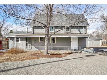 Charming two-story home with gray painted brick, white trim, and a well-maintained front yard and an adjacent two-car garage at 2565 Pierce St, Lakewood, CO 80214