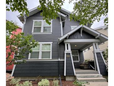 Beautiful two-story home with gray siding, white trim, landscaped yard and a covered front porch with an outdoor seating area at 2857 Xanthia Ct, Denver, CO 80238