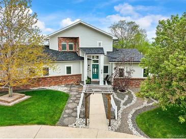 Charming two-story home with a manicured lawn, landscaped garden, and inviting walkway leading to a teal front door at 2161 Elmwood St, Berthoud, CO 80513