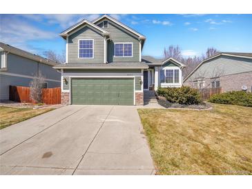 Charming two-story home boasts a well-manicured lawn, complemented by a green two-car garage and stone accents at 5051 Yates Cir, Broomfield, CO 80020