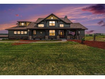 Charming craftsman style home with a covered front porch, green lawn, and mature landscaping under a colorful twilight sky at 1660 Prominence Cir, Elizabeth, CO 80107