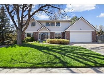Charming two-story home with manicured lawn, mature trees, and brick accents at 7082 W Morraine Dr, Littleton, CO 80128