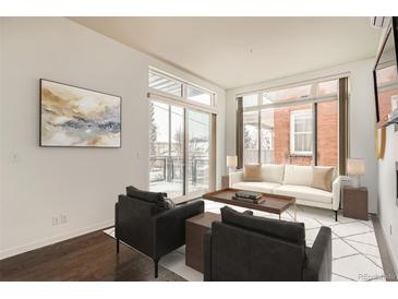 Bright living room with large windows, modern furniture, and dark hardwood floors at 336 E 1St Ave # 200, Denver, CO 80203