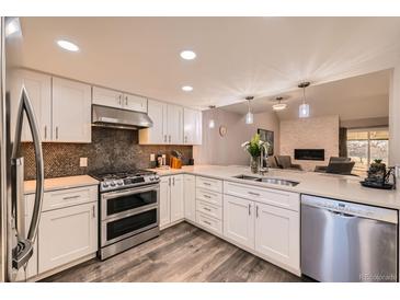 Updated kitchen features white cabinets, stainless appliances, and an open layout to the adjacent living room at 2061 S Worchester Way, Aurora, CO 80014