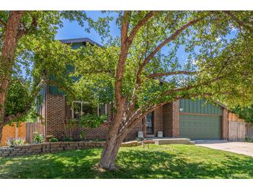 Charming home boasts a brick exterior, lush green lawn, mature tree, and well-maintained landscaping at 9400 W Burgundy Ave, Littleton, CO 80123