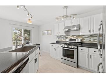 Bright kitchen featuring stainless steel appliances, white cabinets, stone countertops and view to outside at 2545 Andrew Dr, Superior, CO 80027